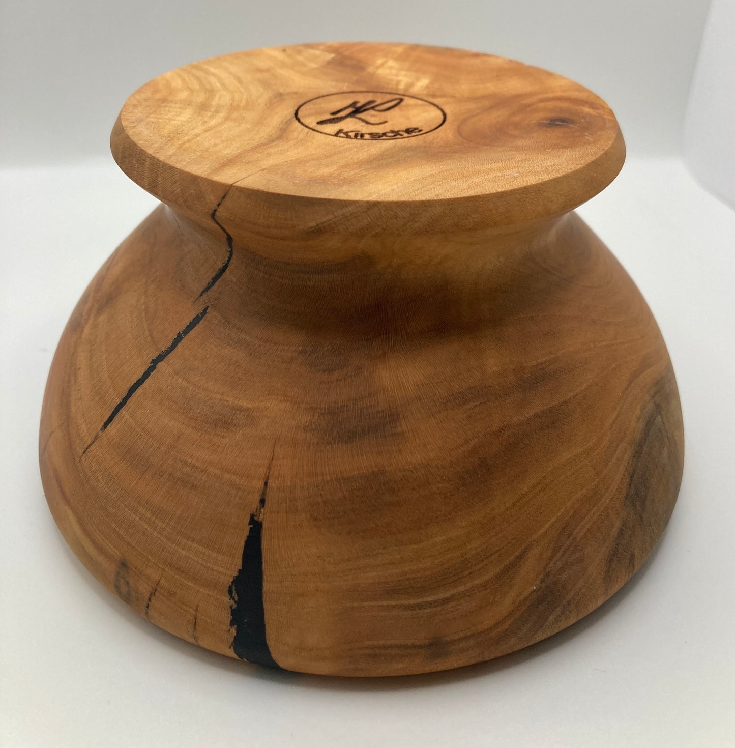 Gedrechselte Schüssel aus Kirschenholz mit Öffnung - zeigt die auf den Kopf gestellte Schüssel seitlich, Unterseite mit Gravur sichtbar; Blick auf die Rückseite ohne Öffnung