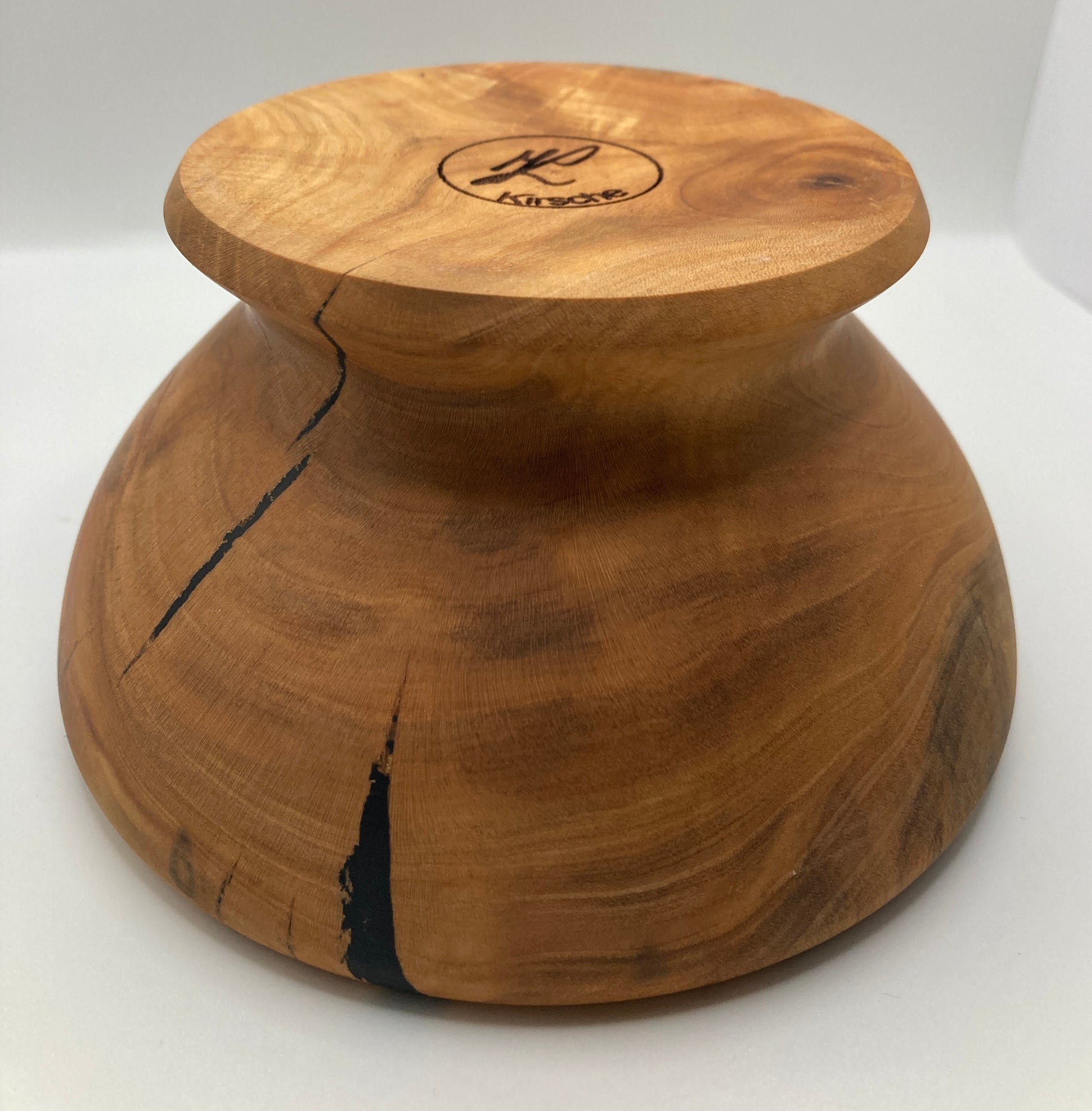Gedrechselte Schüssel aus Kirschenholz mit Öffnung - zeigt die auf den Kopf gestellte Schüssel seitlich, Unterseite mit Gravur sichtbar; Blick auf die Rückseite ohne Öffnung