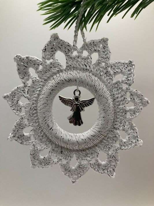 Weißer Häkelstern mit Engel hängt an grünem Tannenzweig