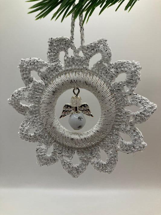 Weißer Häkelstern mit Engel hängt an grünem Tannenzweig